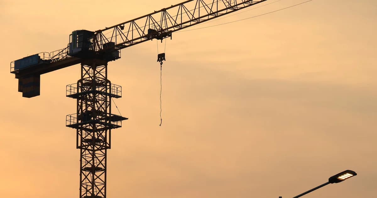 Turmdrehkran als Silhouette vor Abendhimmel auf einer Baustelle