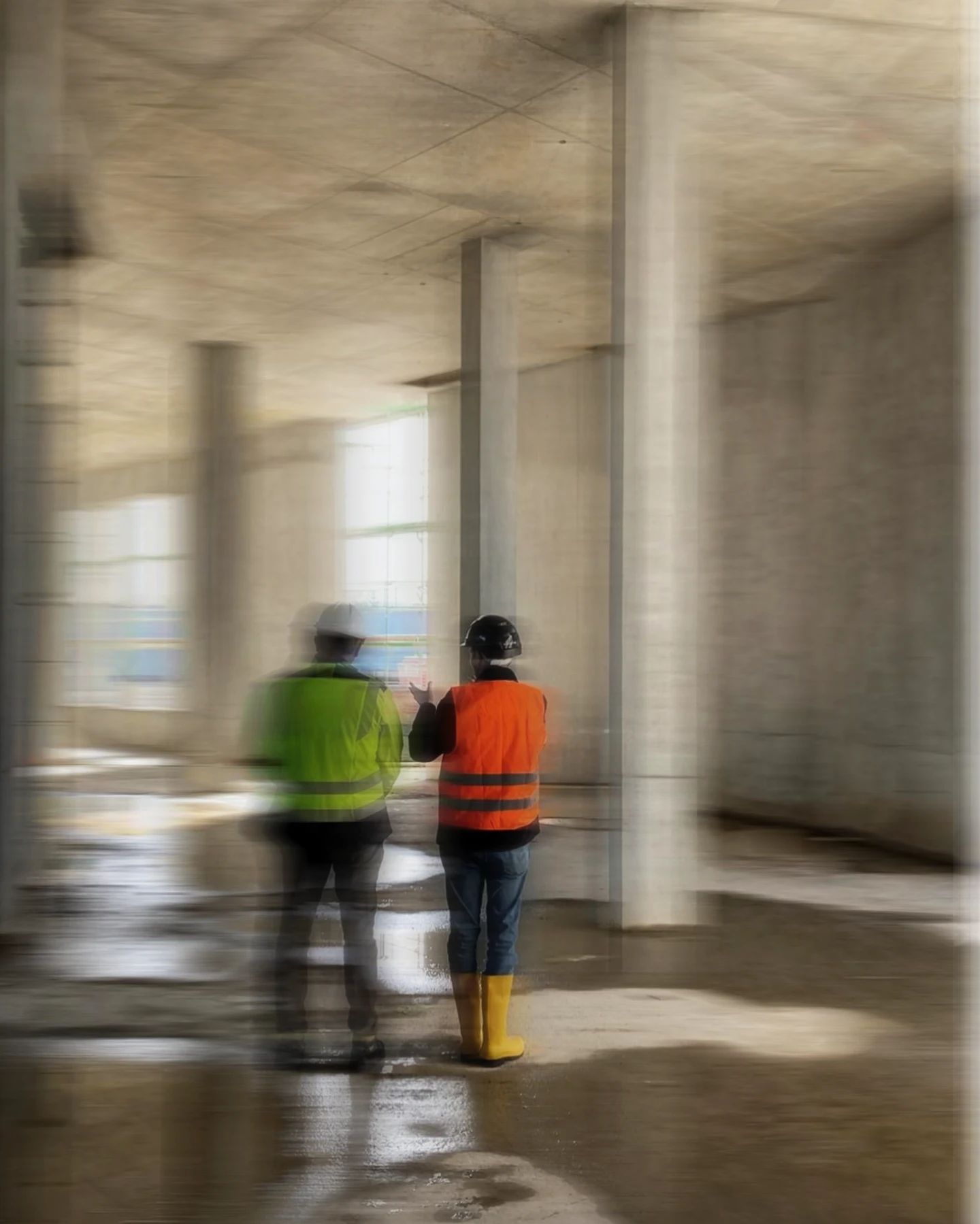 Two workers in hi-vis vests on a concrete structure under construction